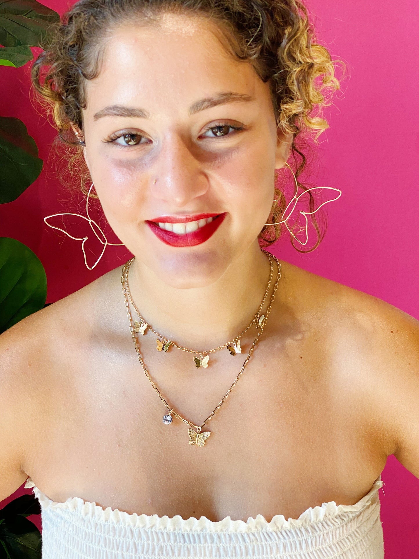 A farther away image of how the gold Butterfly Colony Necklace looks around the neck and his it can be paired with a longer necklace for a stackable look.