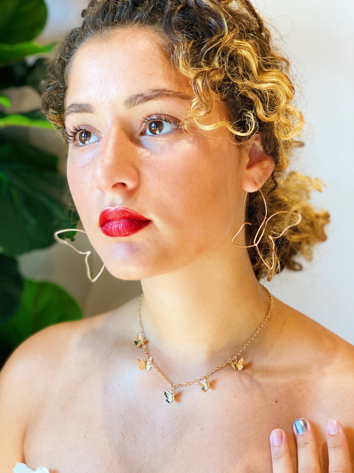 The gold butterfly colony necklace shown around a woman’s neck showing the length and size of the gold butterflies.