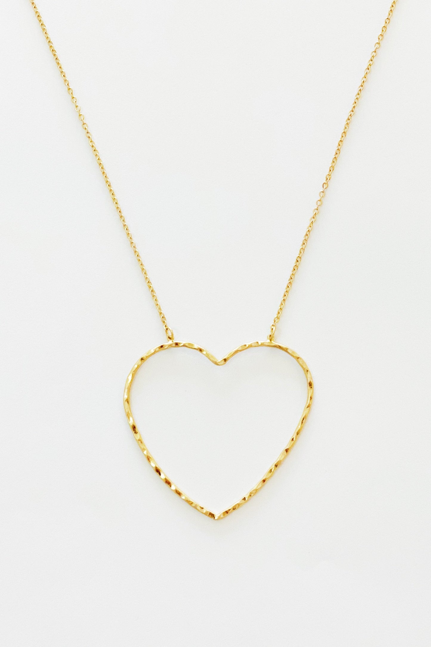 gold chain necklace with hammered heart pendant displayed on white background