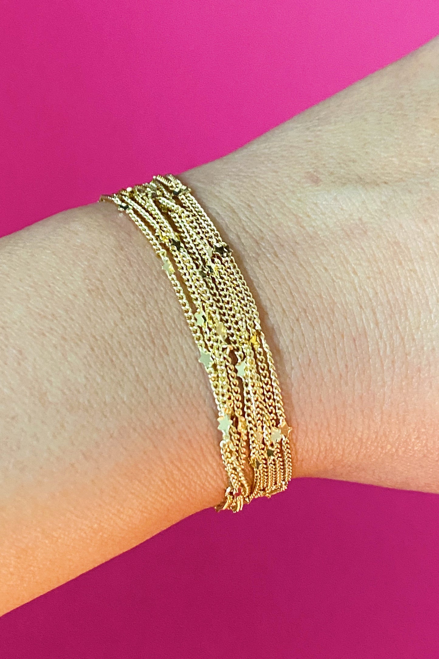 Woman wearing gold chain necklace with tiny star charms wrapped around bracelet