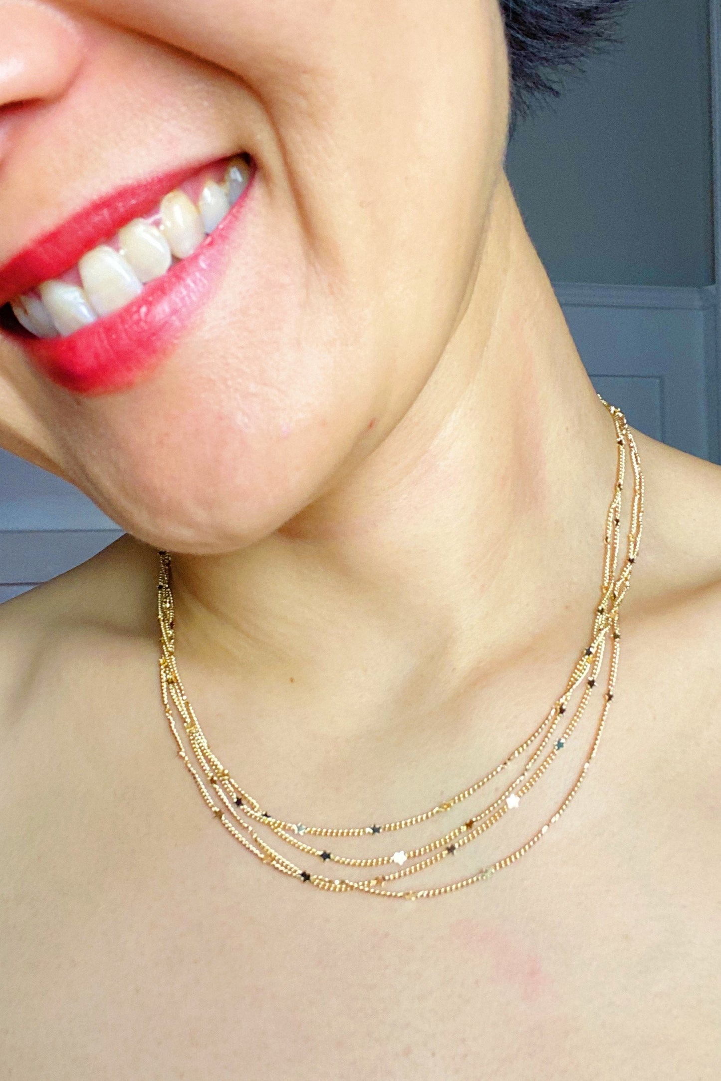 Woman wearing layered gold chain necklace with tiny star charms