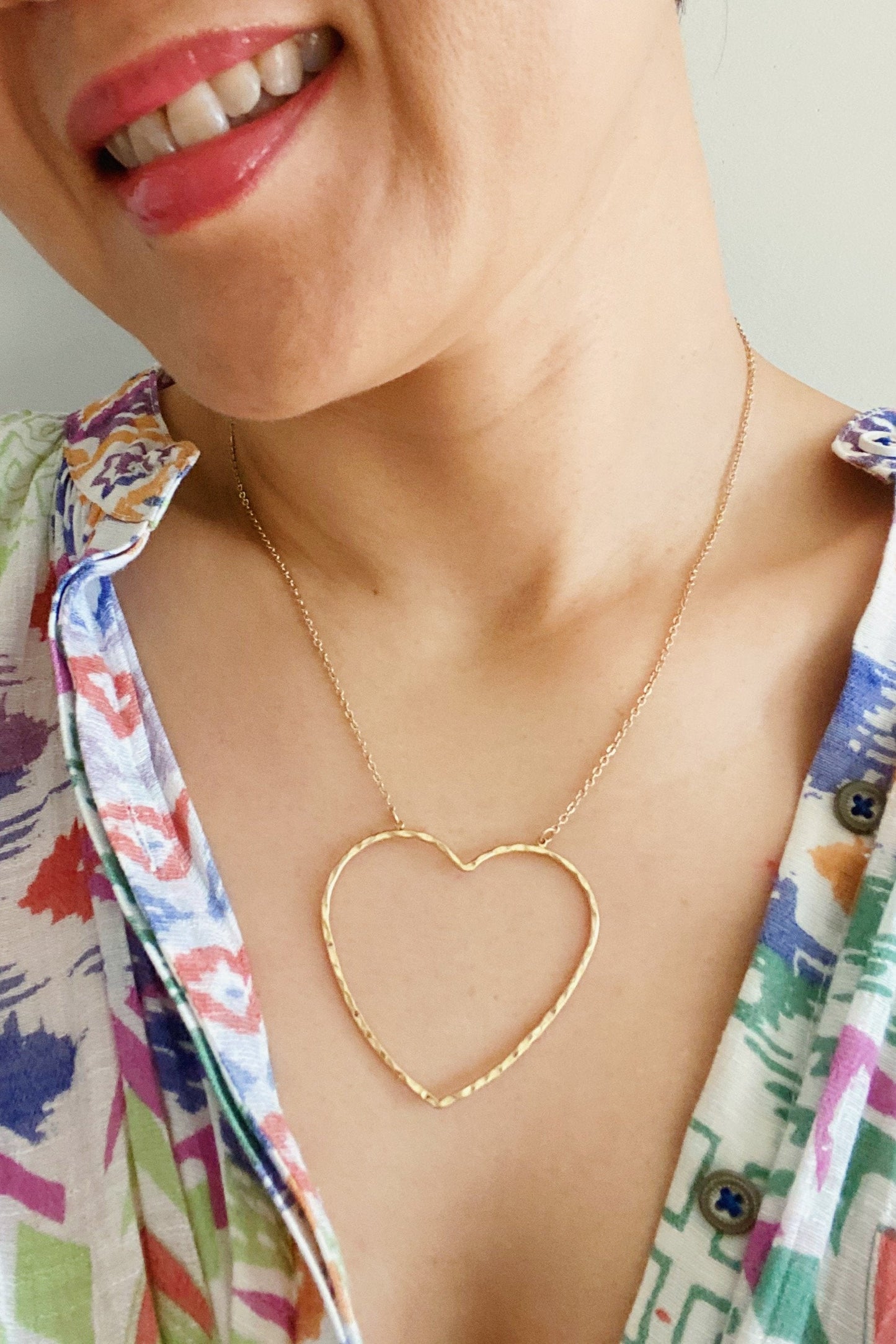 Woman wearing gold chain necklace with hammered heart pendant
