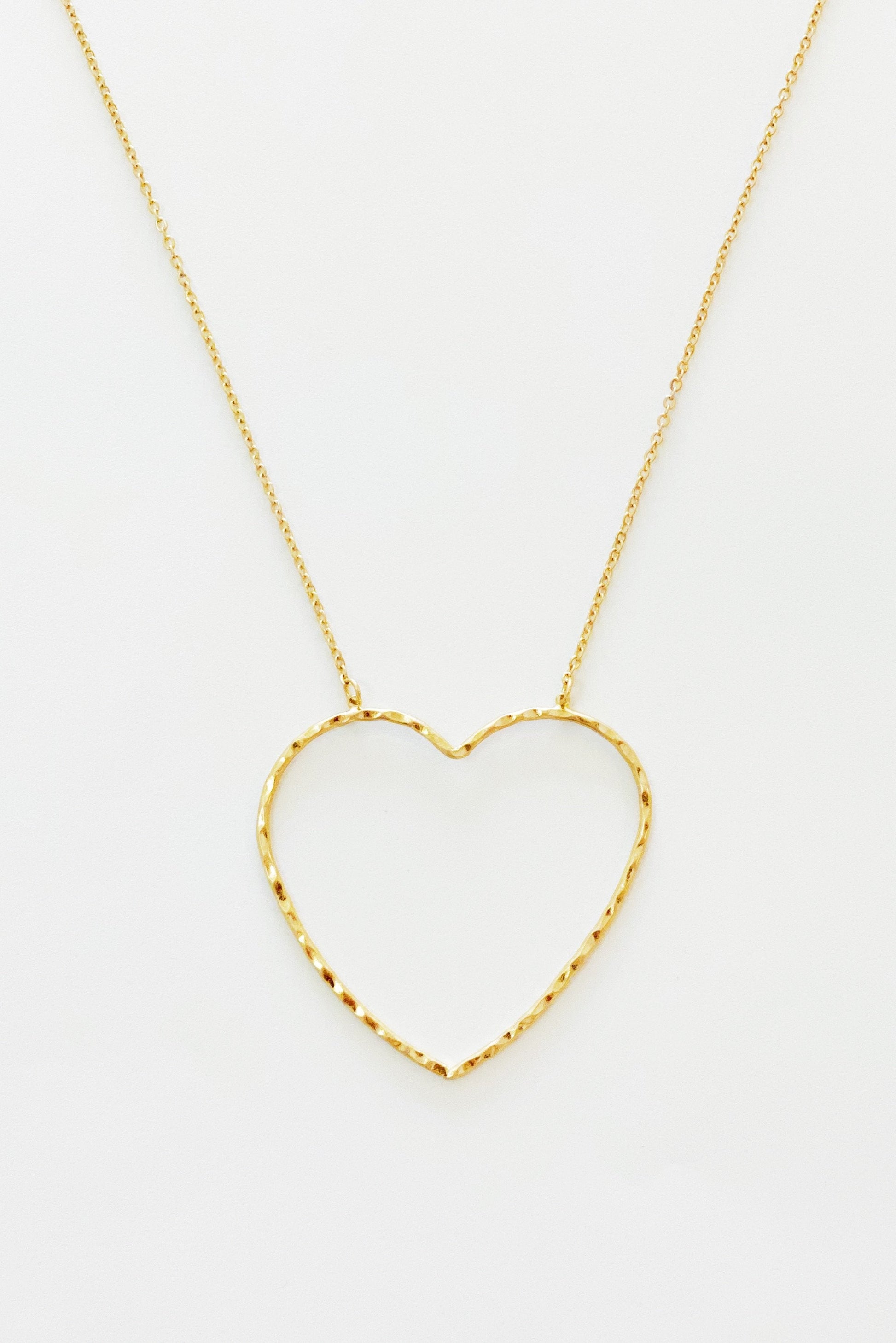 gold chain necklace with hammered heart pendant displayed on white background